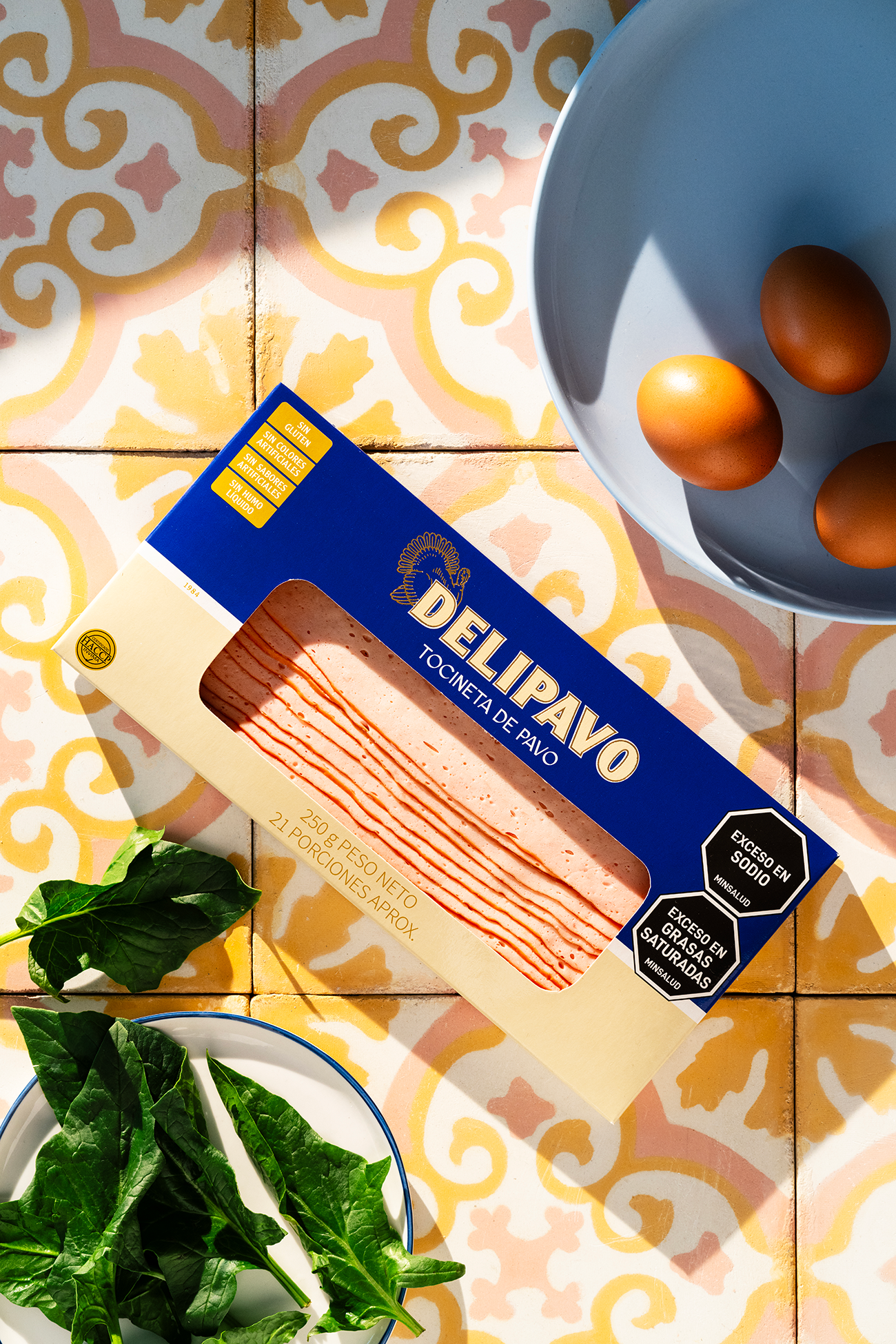 Imagen del empaque de Tocineta de Pavo Delipavo sobre una mesa con ingredientes frescos.